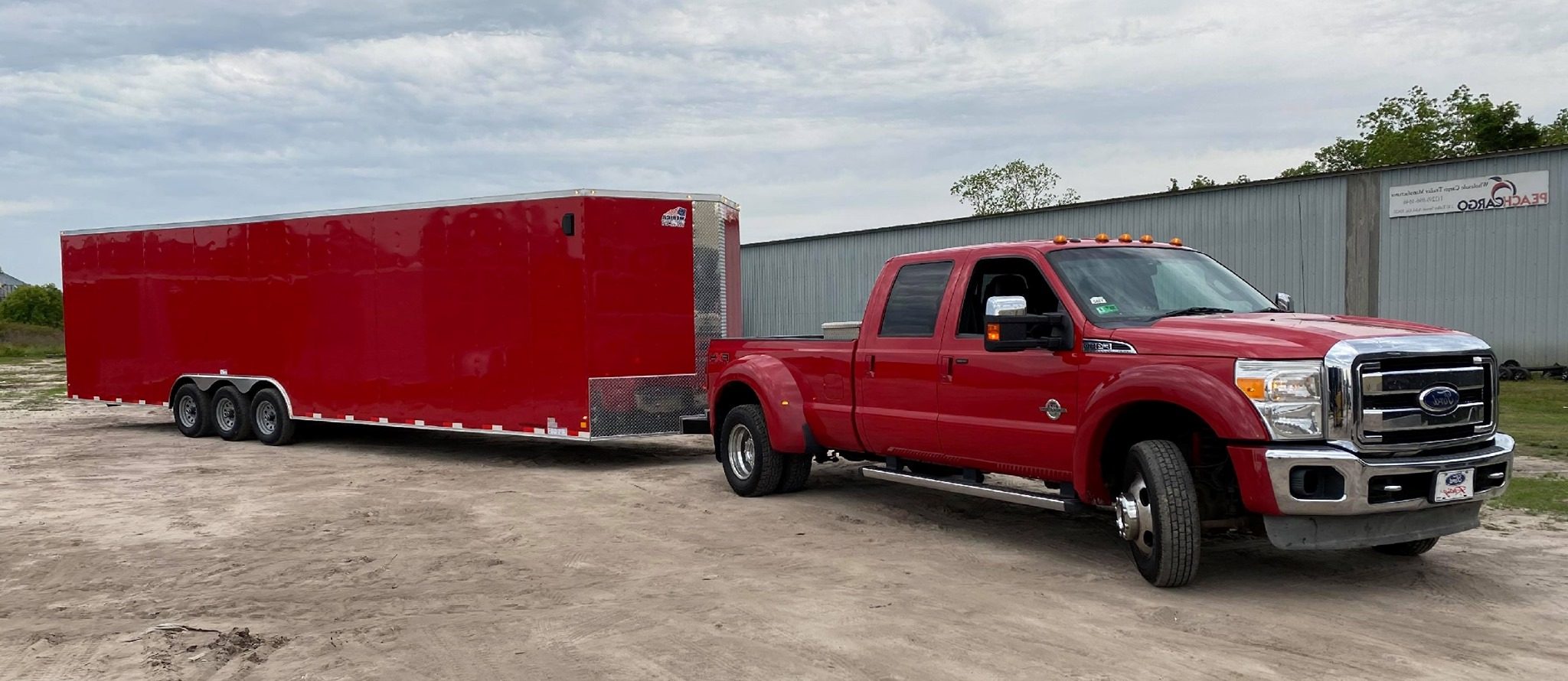 Long red enclosed trailer pulled by a red Pickup